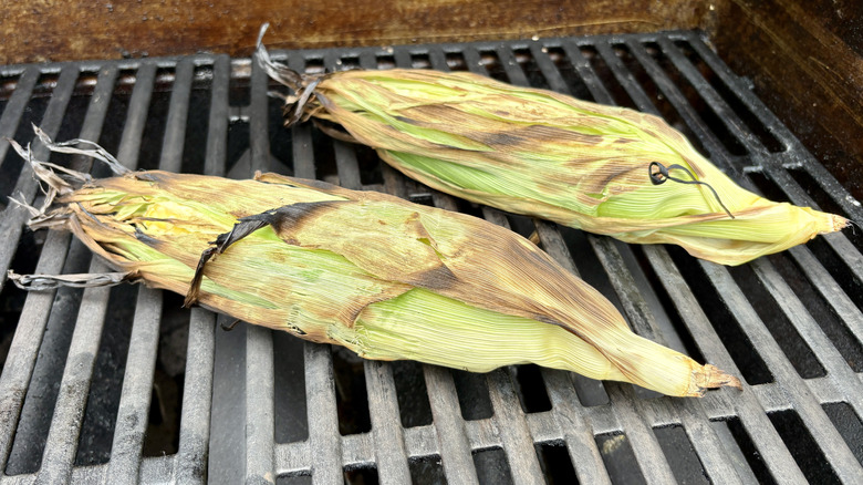 Two ears of corn in husks on the grill