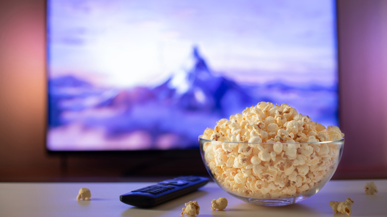 A bowl of popcorn on a table in front of the television