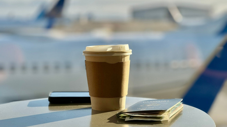 Coffee cup on an airport table with passport next to it