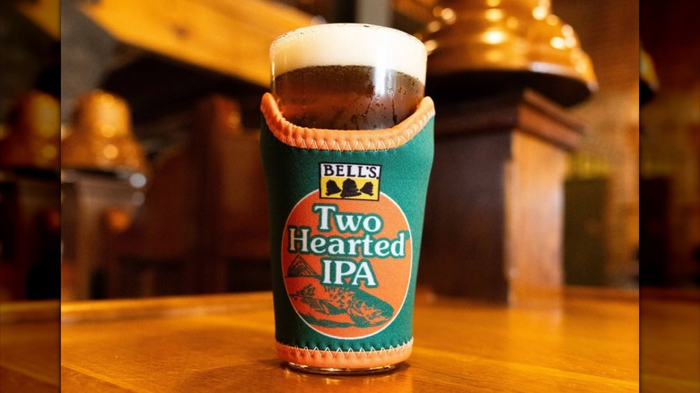 Bell's Two-Hearted IPA beer koozie over a glass.