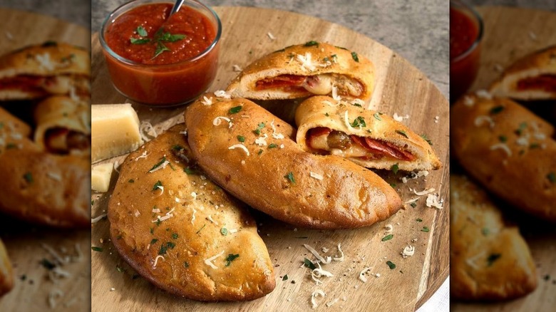 Cooked Member's Mark calzones with a small bowl of marinara sauce
