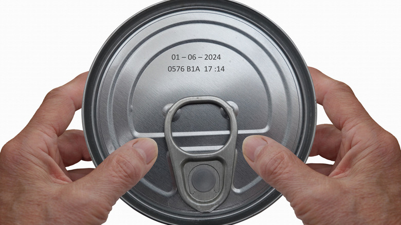 Hands holding can with date printed on the lid
