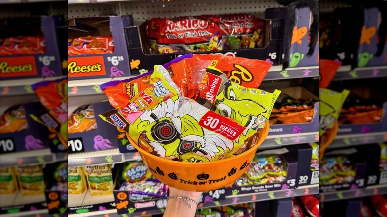 Person holding a plastic bowl with bagged Halloween candy inside Dollar General.