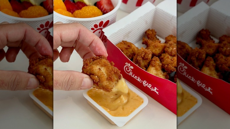 Hand dipping Chick-fil-A nugget into sauce with the box of nuggets in the backgroud