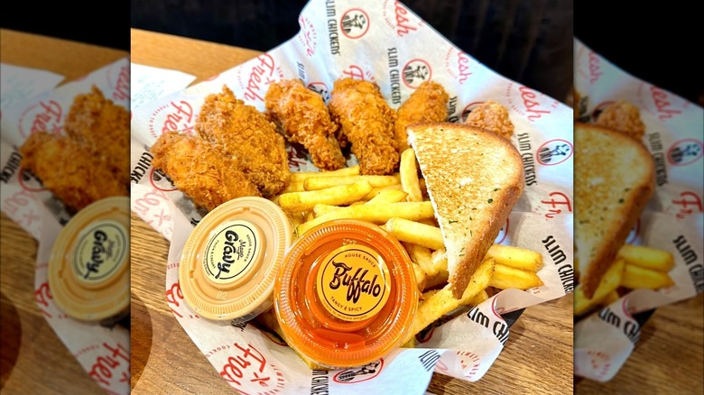 Basket of chicken bites, fries, and Texas toast on a wooden table