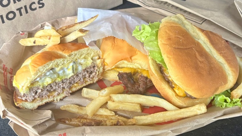 Three cheeseburgers with fast food bags and French fries