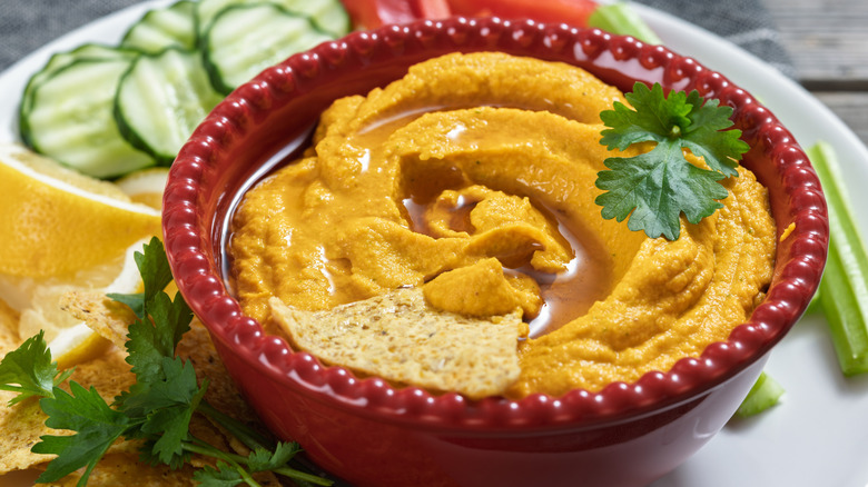 Red dish of fresh hummus with vegetables