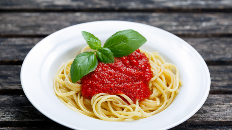 White bowl of spaghetti with red sauce