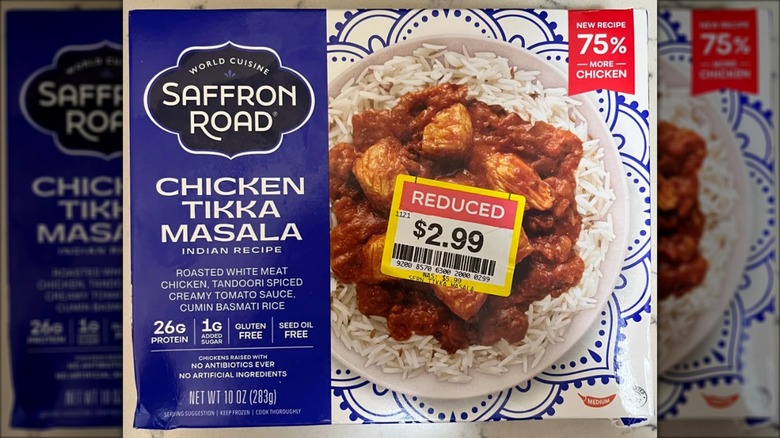 A Saffron Road frozen dinner of chicken tikka masala is packaged in a white and purple box.
