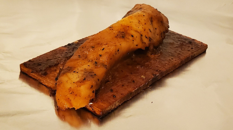 A cooked salmon fillet on a cedar plank