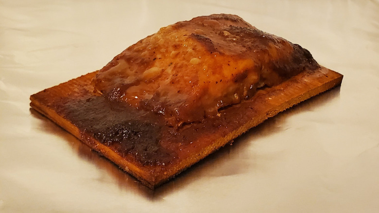 A cooked salmon fillet on a cedar plank