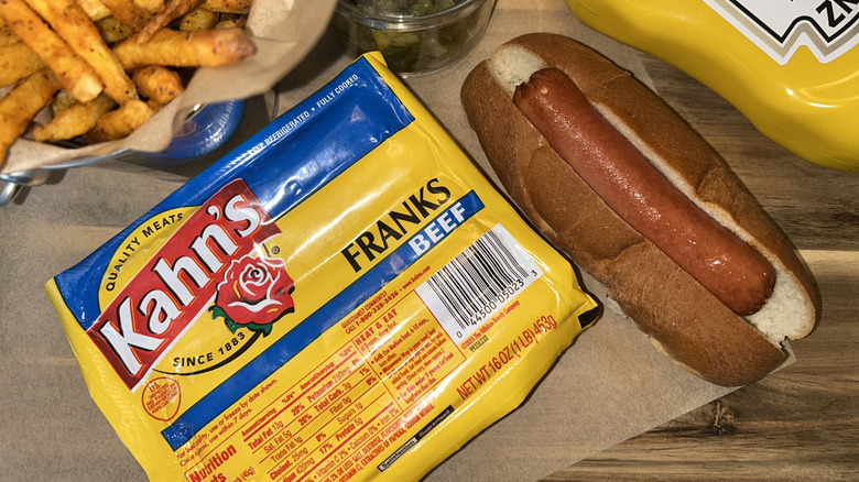 Khan's hot dogs with hot dog in a bun, mustard, fries and relish in the background