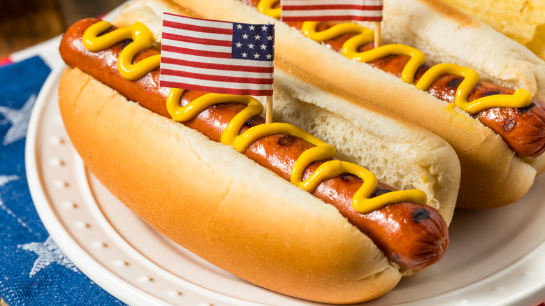 two hot dogs on buns with mustard and American flags