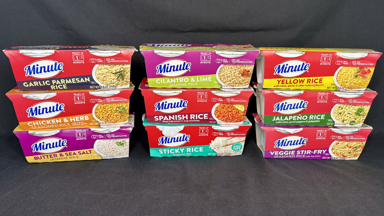 Nine packages of Minute Rice stacked on black background