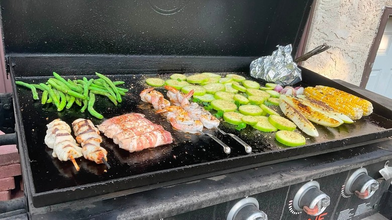Blackstone griddle with cooking zones established for shrimp, chicken, and vegetables