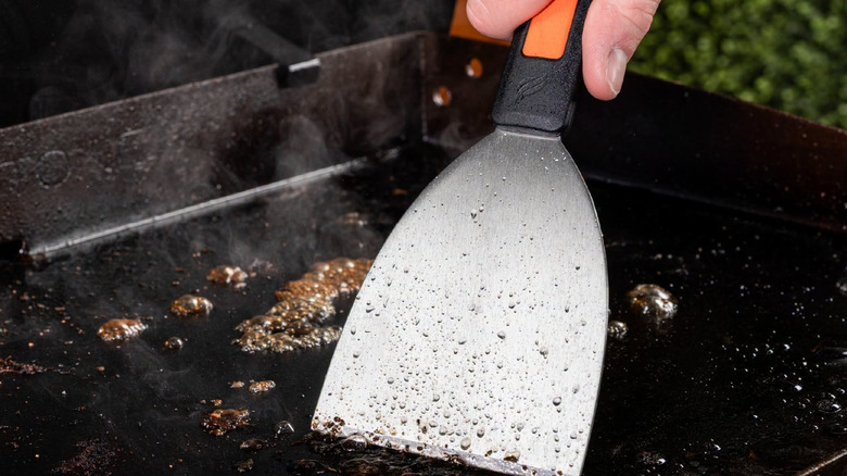 Close up of person's hand scraping grease