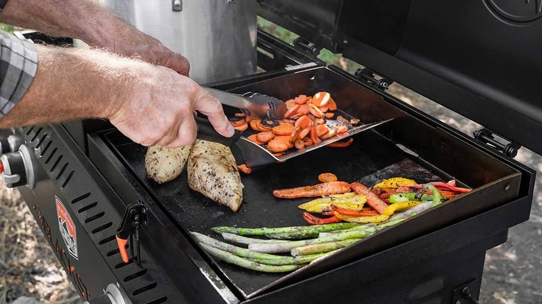 Man's hands stirring food on a small Blackstone