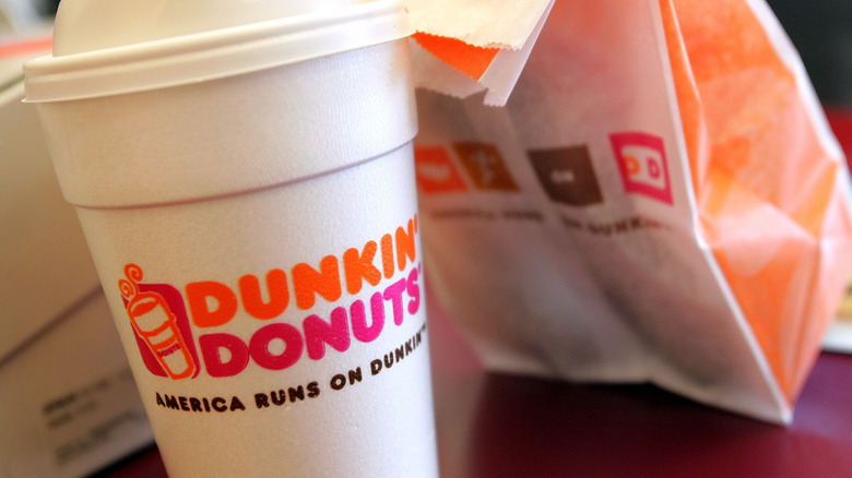 Close up of Dunkin Donuts coffee in styrofoam cup and donut bag
