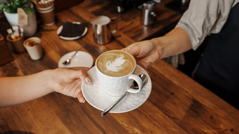 barista handing customer a cafe latte