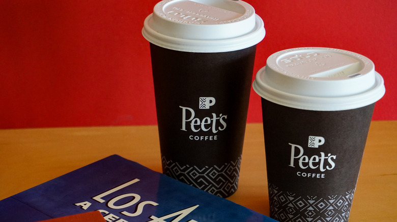 Two Peets Coffee paper coffee cups with lids on table