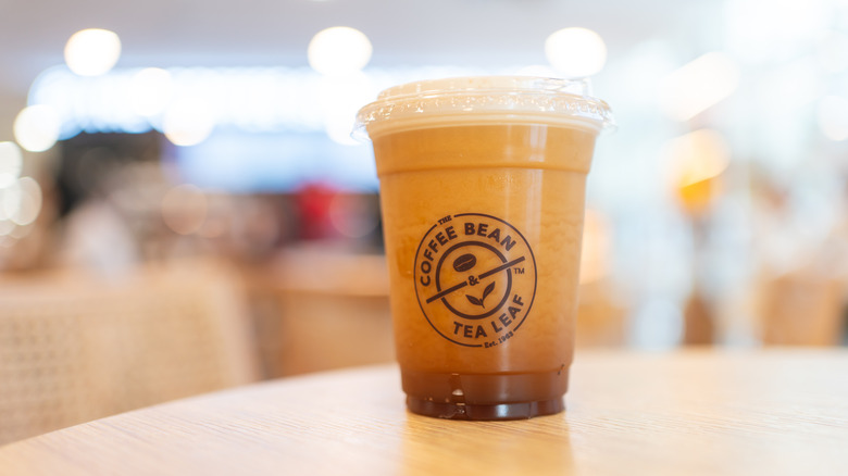 Coffee Bean and Tea Leaf iced coffee drink in plastic takeout cup on table in coffee shop