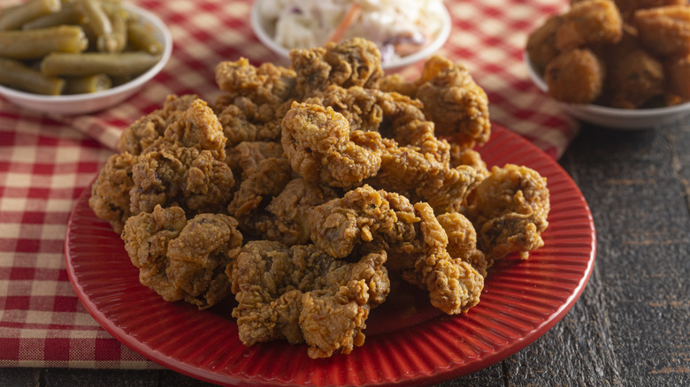 A plate of Southern fried chicken gizzards on a checkered tablecloth with side dishes