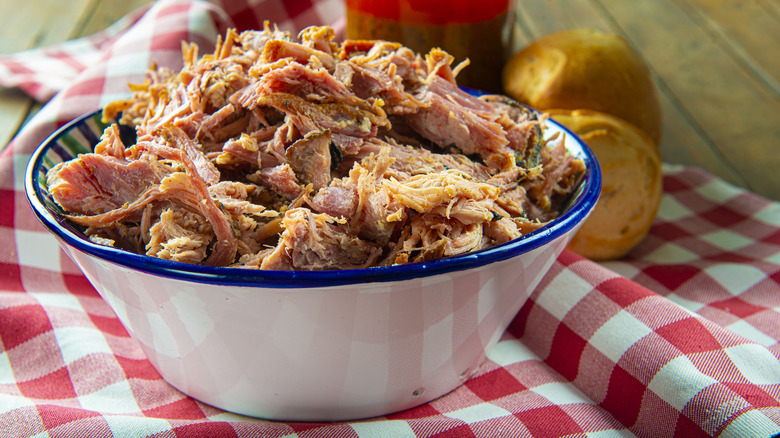 pulled pork made with vinegar sauce in bowl on checkered tablecloth