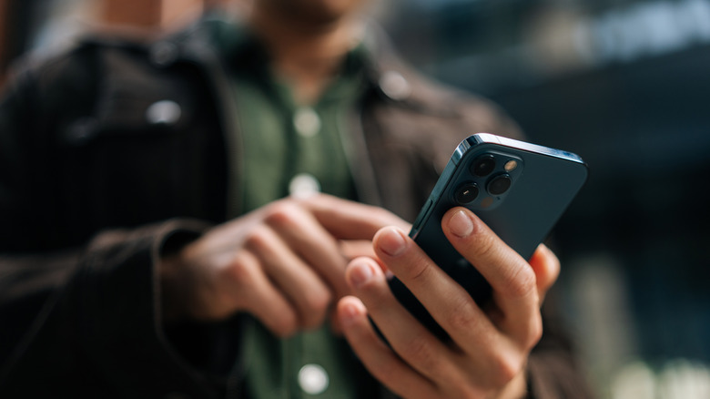 A close-up of hands holding and typing on a phone