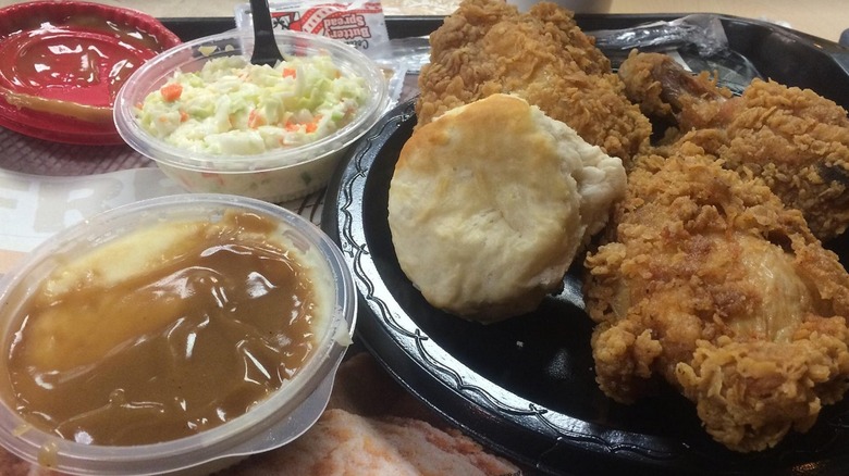 KFC meal with fried chicken, mashed potatoes and gravy, and coleslaw in plastic to-go containers