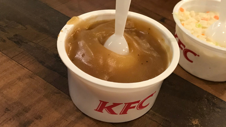 To-go cup of KFC mashed potatoes and coleslaw with plastic spoons in them