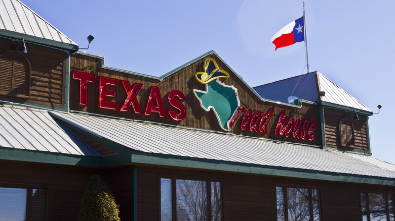 Exterior of a Texas Roadhouse restaurant, with signage and Texas flag