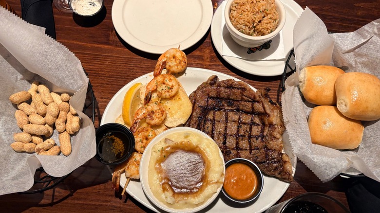 Texas Roadhouse table filled with peanuts, steak, shrimp, potatoes, rice, and rolls
