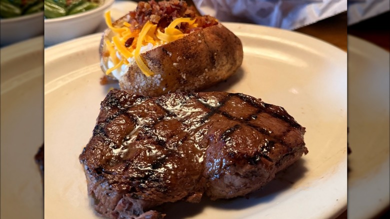 A Texas Roadhouse grilled steak with loaded baked potato