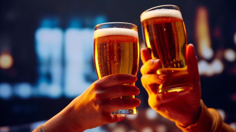 Hands toasting two pints of beer.