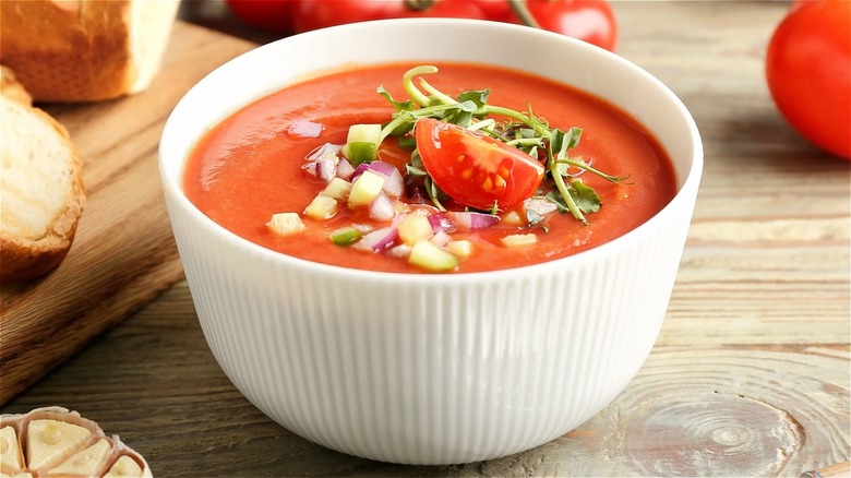 Tomato soup topped with veggies in white bowl