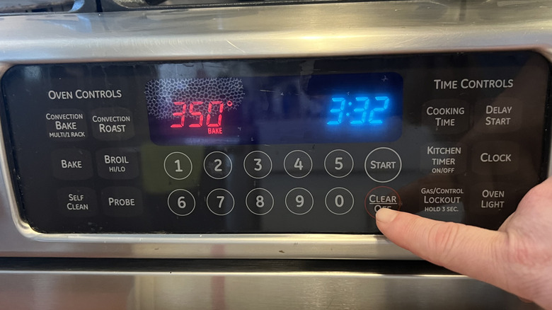 hand touching oven temperature gauge