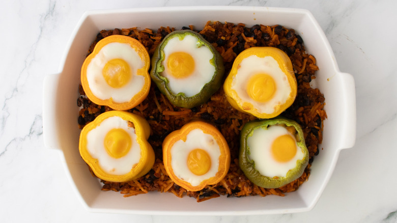 bell peppers with cooked eggs in a white baking pan