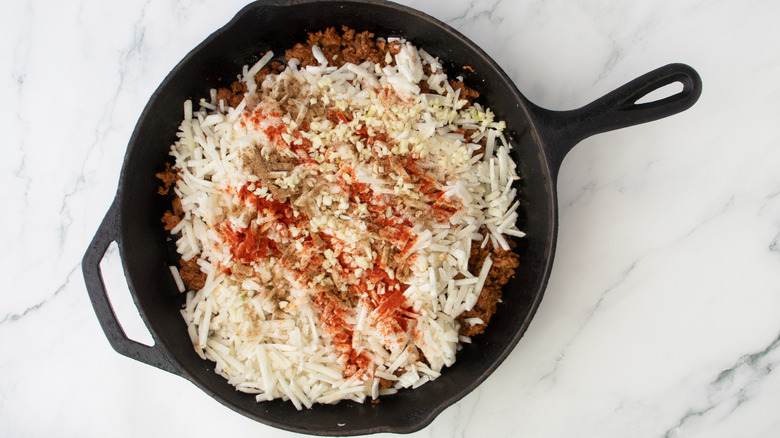 shredded potatoes and ground meat in black frying pan