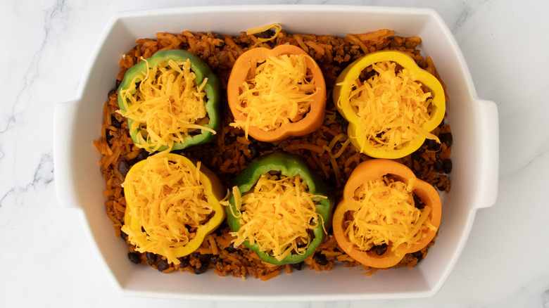 cheese-topped bell peppers in a white baking pan