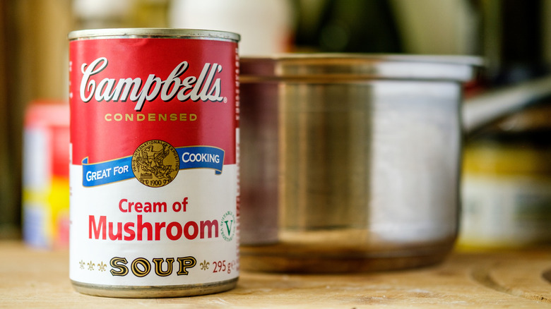 A can of cream of mushroom soup next to a pot.