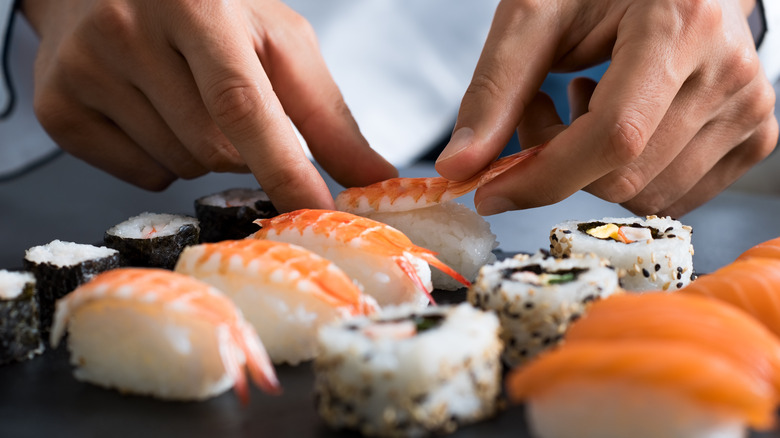 hands preparing sushi rolls