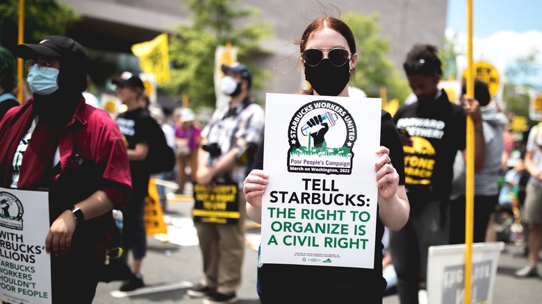 Woman holding sign on picket line at Starbucks.