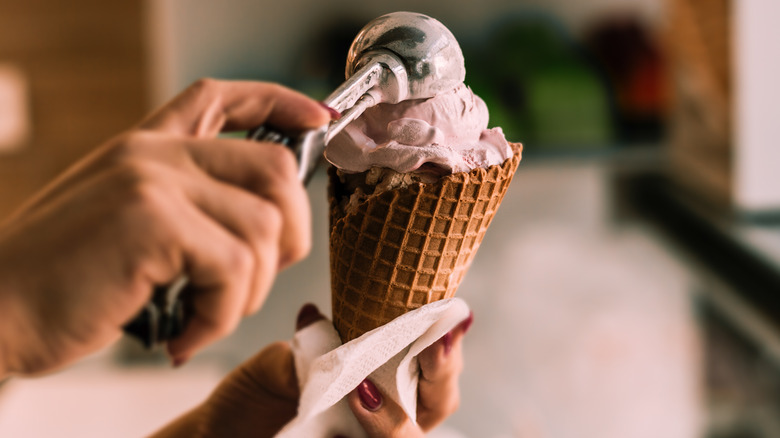 Hand scooping ice cream in cone