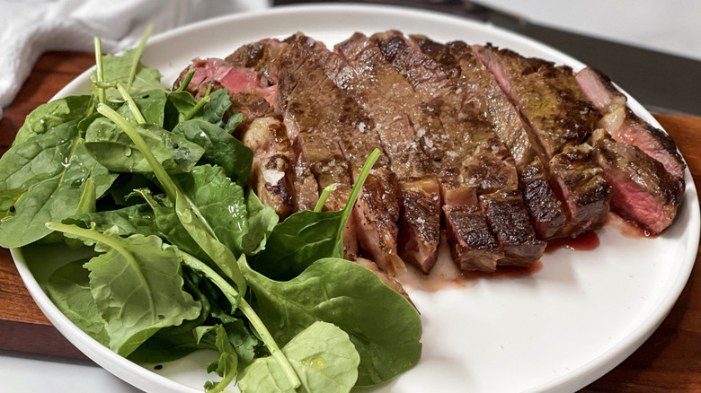Sliced steak on plate with leafy green salad