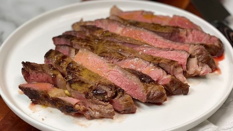Sliced steak on plate with miso butter and flaky salt garnish