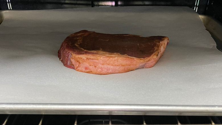 Steak on baking sheet in oven