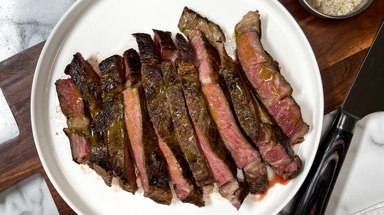 Sliced steak on plate topped with melted butter
