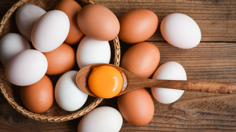 cracked egg yolk over white and brown eggs