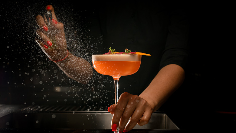 Person making an orange cocktail