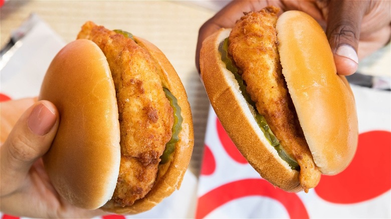 Two people holding Chick-fil-A chicken sandwiches